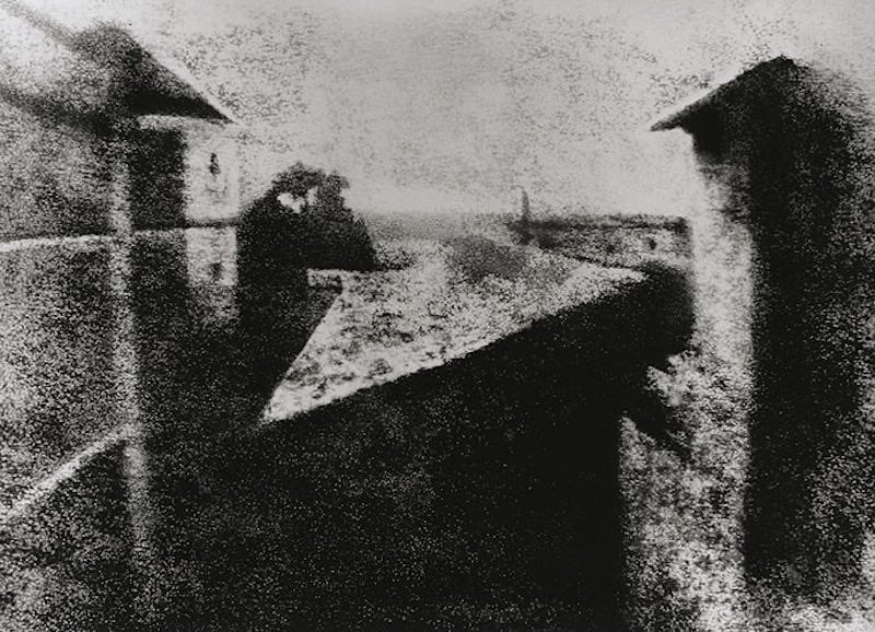 Vista desde la ventana en Le Gras, de Joseph Nicéphore Niépce, 1827: edificios y tejados apenas distinguibles en la fotografía histórica en blanco y negro.